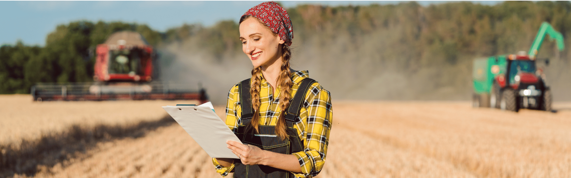 Farmer in field checking off to do list with tractors behind her