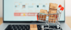 mini e-commerce shopping cart with boxes sitting on a laptop keyboard